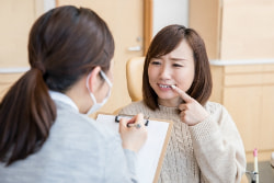 自分の歯を指差す女性の写真