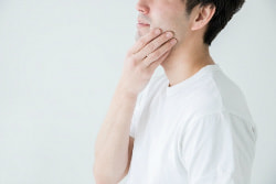 顎をおさえている男性の写真