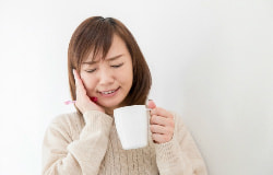 頬をおさえている女性の写真